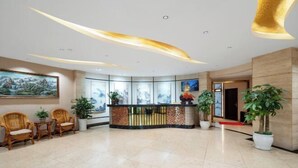 A modern lobby with a reception desk, seating area, and potted plants. - Shengkai Business Hotel (Chongqing)