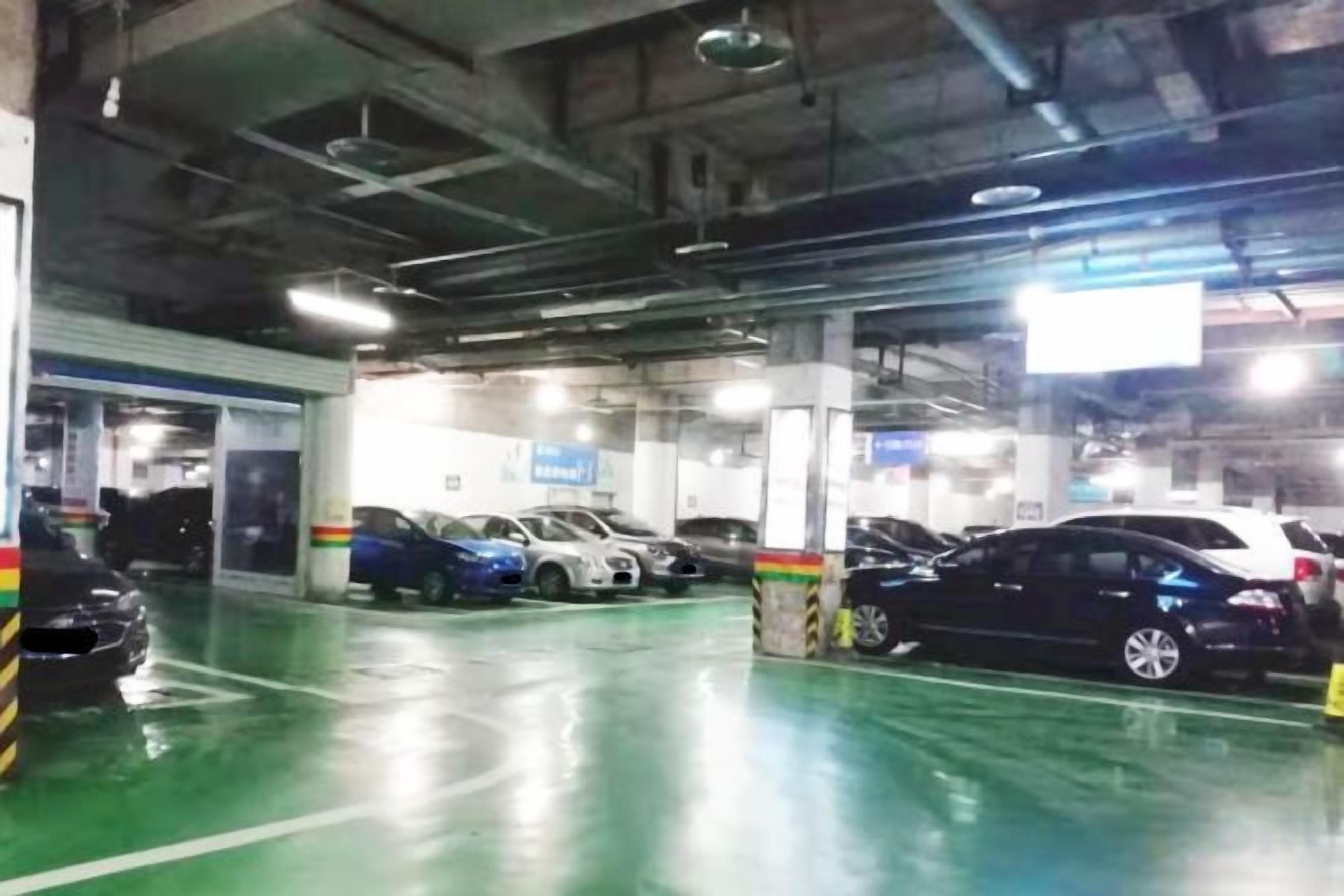 An indoor parking garage with multiple levels, concrete pillars, and a green floor.