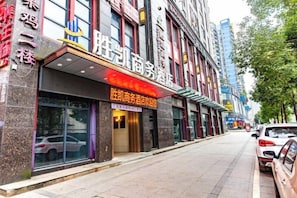 A hotel facade with a prominent sign, large windows, and a parking area. - Shengkai Business Hotel (Chongqing)