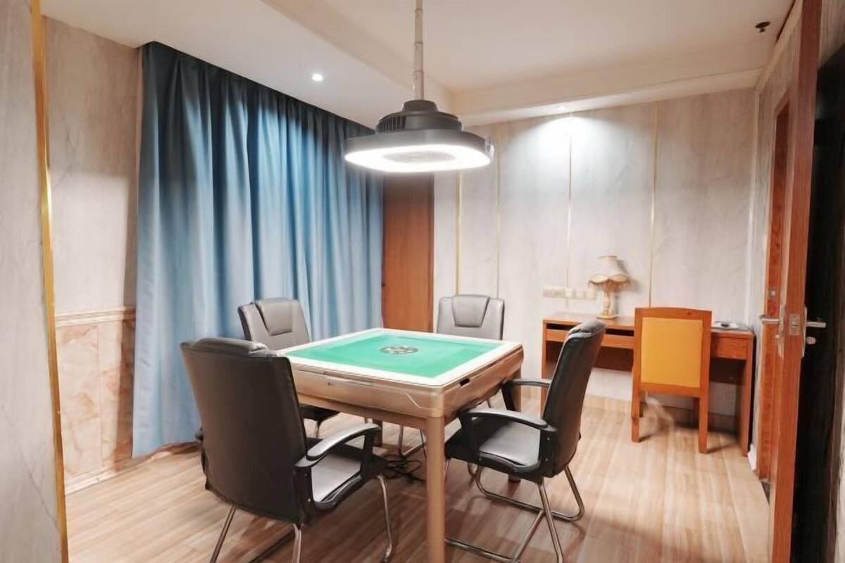 A room with a pool table, four chairs, a lamp, and a wooden desk.