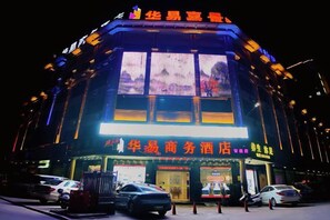 Edifício bem iluminado, com grandes janelas e placas indicando que se trata de um estabelecimento comercial.