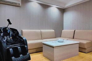 A modern room with a beige sofa, a massage chair, and a coffee table. - Huayi Business Hotel (Jieyang)