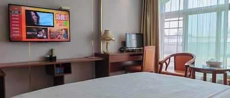 Una habitación de hotel con una cama, un escritorio con televisor, una lámpara y una silla.