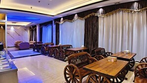 Un restaurant avec des tables et des chaises en bois, un sol en marbre et des rideaux.
