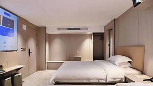 Une chambre d’hôtel avec un grand lit, un bureau et un écran de projection.