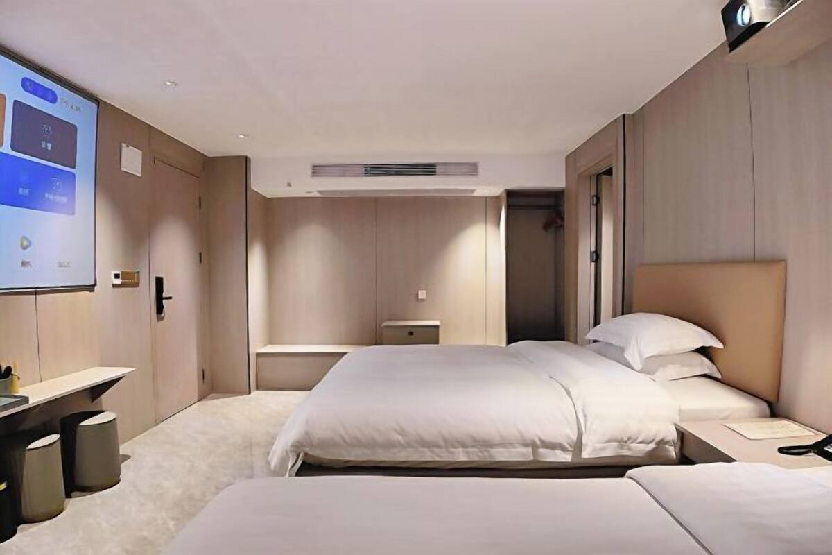 A hotel room with a large bed, a desk, and a projector screen.