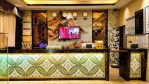 Un hall d’hôtel avec un comptoir d’accueil décoré, un téléviseur fixé au mur et un mur décoratif orné d’horloges.