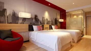 Una moderna camera d'hotel con due letti, una poltrona rossa, un murale con una vista sulla città e un box doccia in vetro.