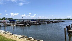 Una marina con barcos amarrados, cielo despejado y aguas tranquilas.