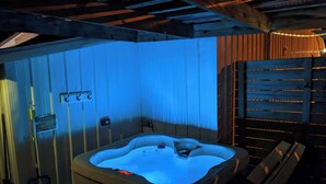 Un jacuzzi en una habitación de madera con un banco y un calentador en la pared.