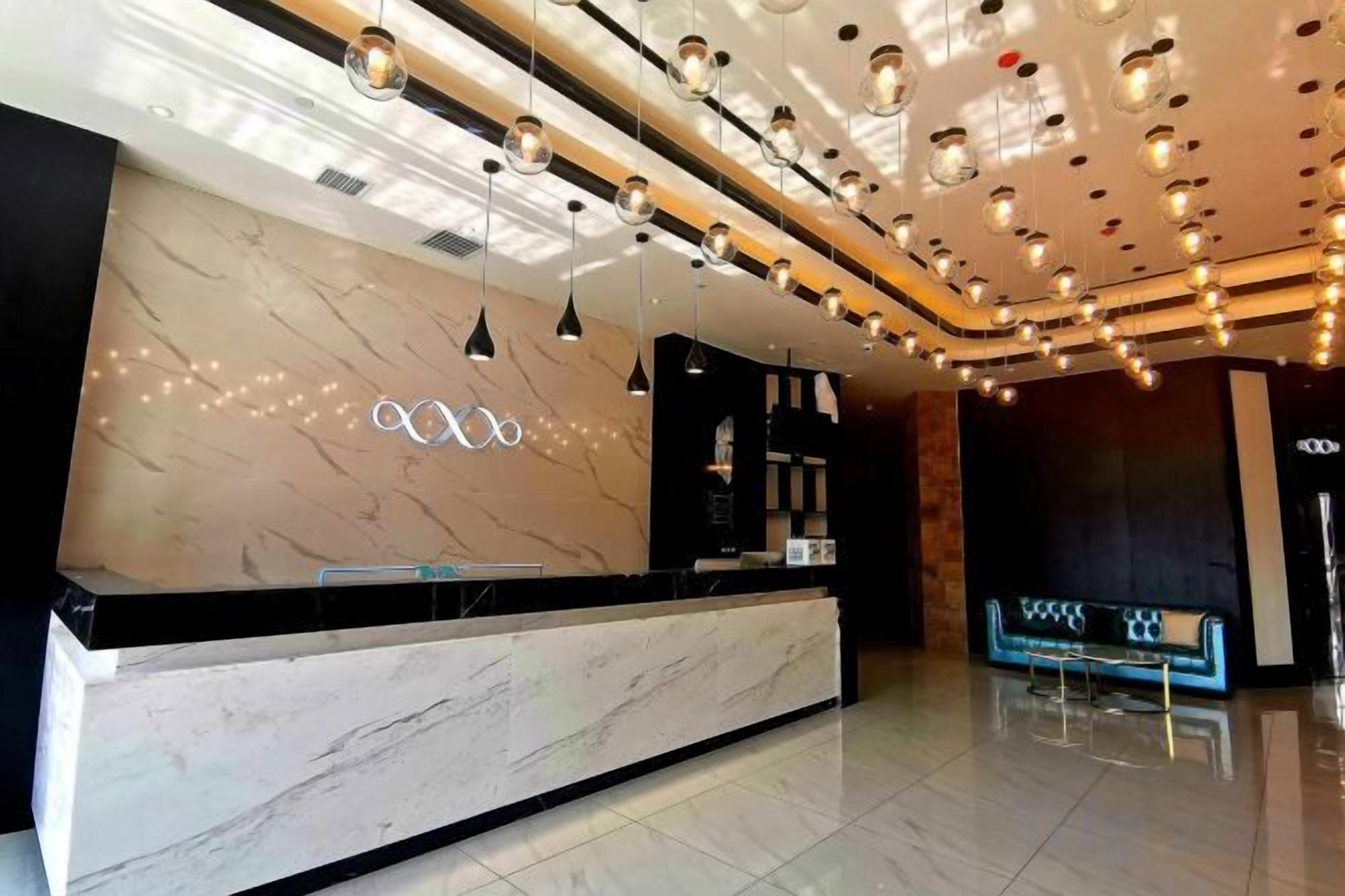 A hotel reception area with a marble counter, pendant lighting, and a modern ceiling design.