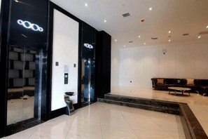 A modern hotel lobby with a reception desk, seating area, and a large mirror. - Wanpeng Xiting Hotel (Yanchuan)