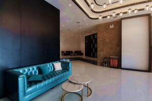 A modern lobby with a blue leather sofa, a marble coffee table, and a reception desk. - Wanpeng Xiting Hotel (Yanchuan)