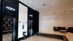 Un hall d’hôtel moderne comprenant un comptoir d’accueil, un espace salon et un escalier menant à l’étage supérieur.