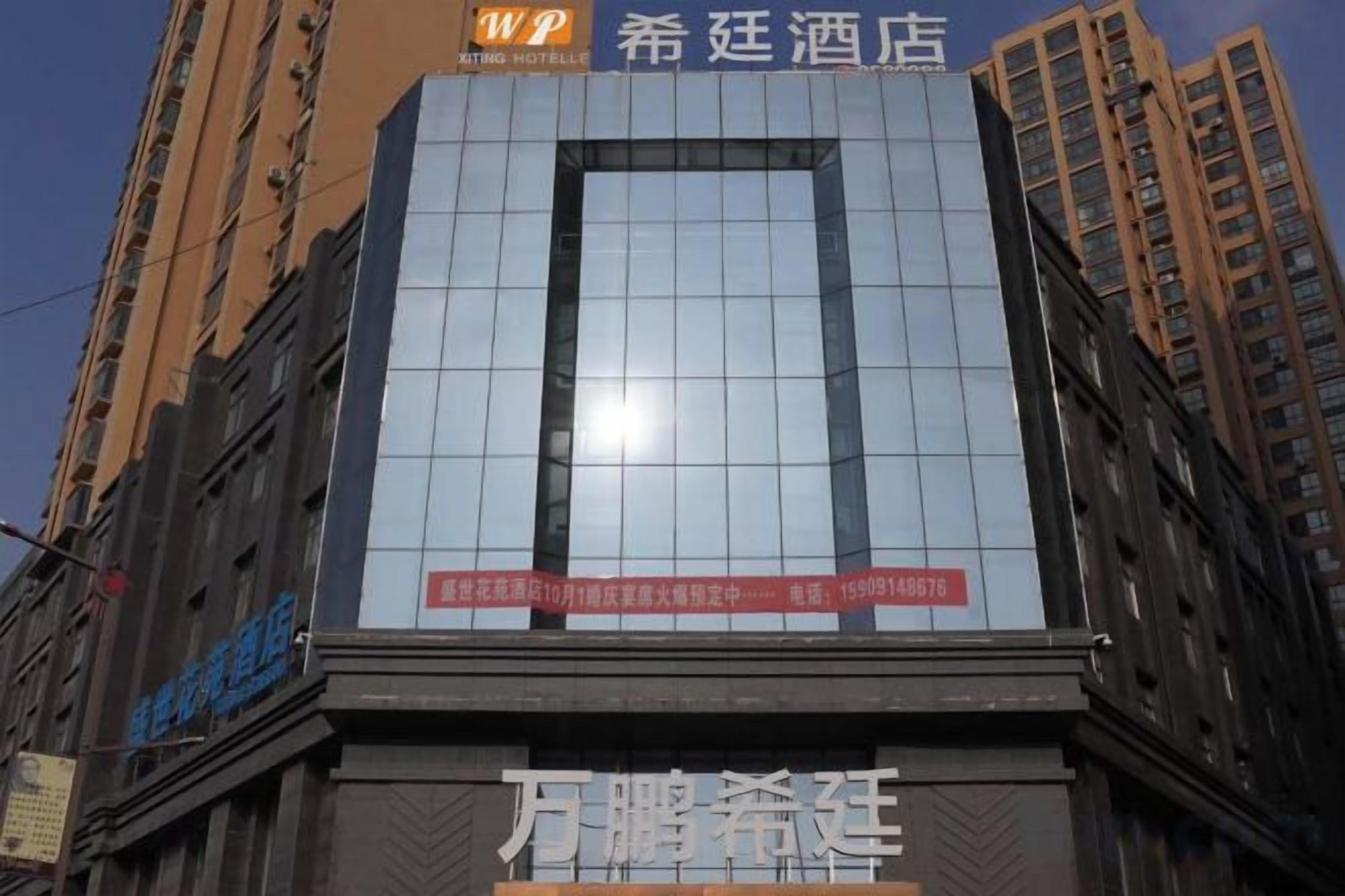 A hotel with a modern glass facade, a prominent sign, and a clear view of the surrounding urban environment.