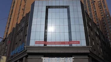 A hotel with a modern glass facade, a prominent sign, and a clear view of the surrounding urban environment.