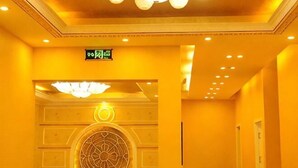 A hotel lobby with a circular decorative wall, a chandelier, and a sign indicating the exit.