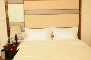 Quarto de hotel com uma cama, mesa de cabeceira, luminária e lixeira.