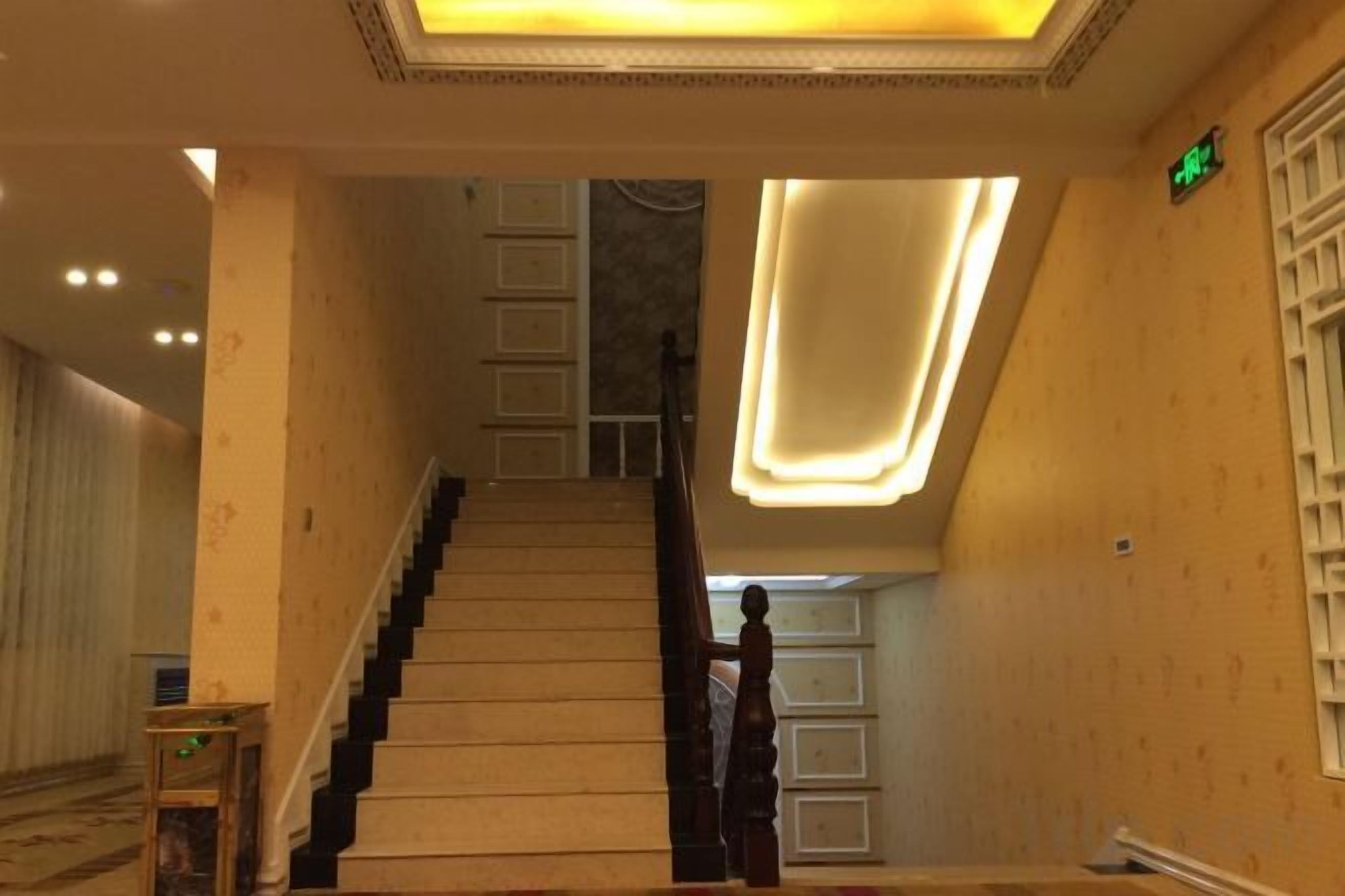 Una escalera con barandilla, una pared con lámpara y una puerta con manija.