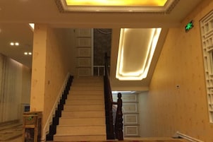 Una escalera con barandilla, una pared con lámpara y una puerta con manija.