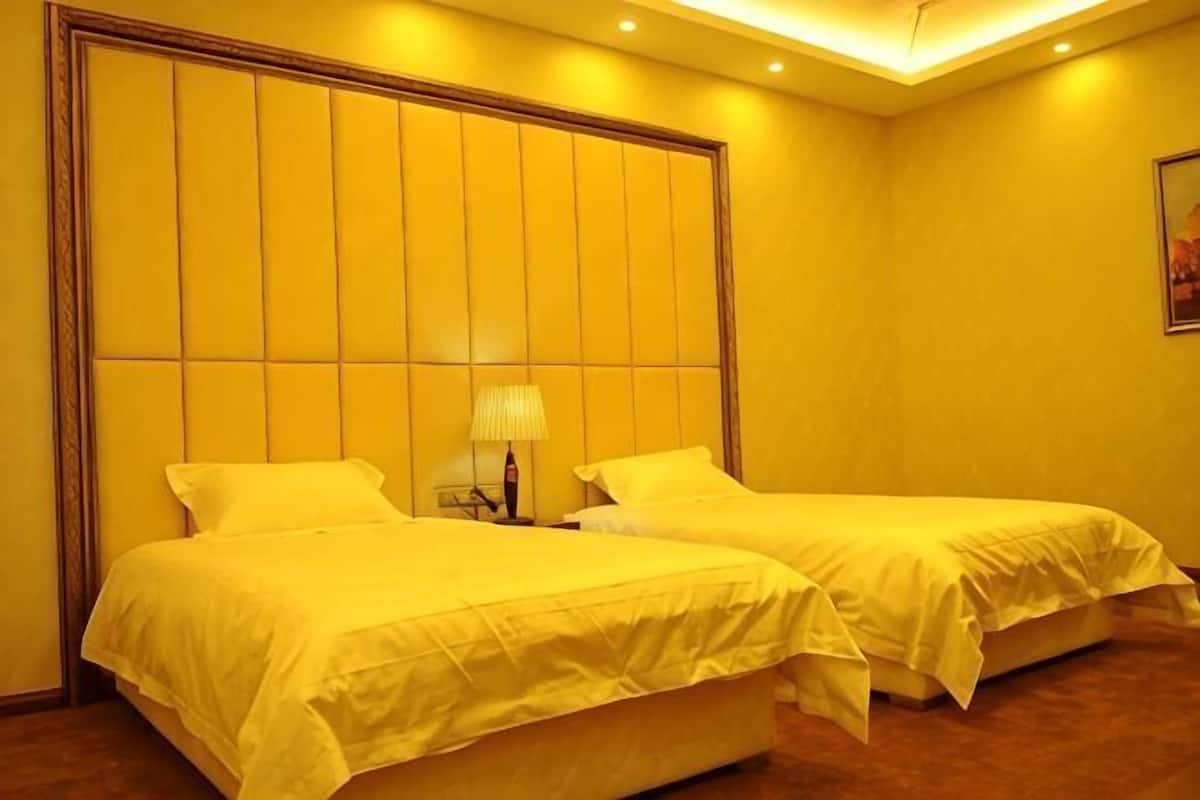 Une chambre d’hôtel avec deux lits, une table de chevet et une lampe fixée au mur.