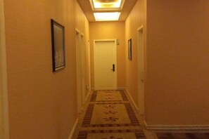 A hallway with carpeted flooring, framed pictures on the walls, and a door at the end. - Tianliyuan Hotel (Genhe)