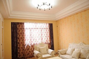 A room with a chandelier, a sofa, and a chair.