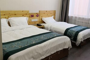Habitación de hotel con dos camas individuales, cabeceros de madera, ropa de cama blanca y una ventana con cortinas.