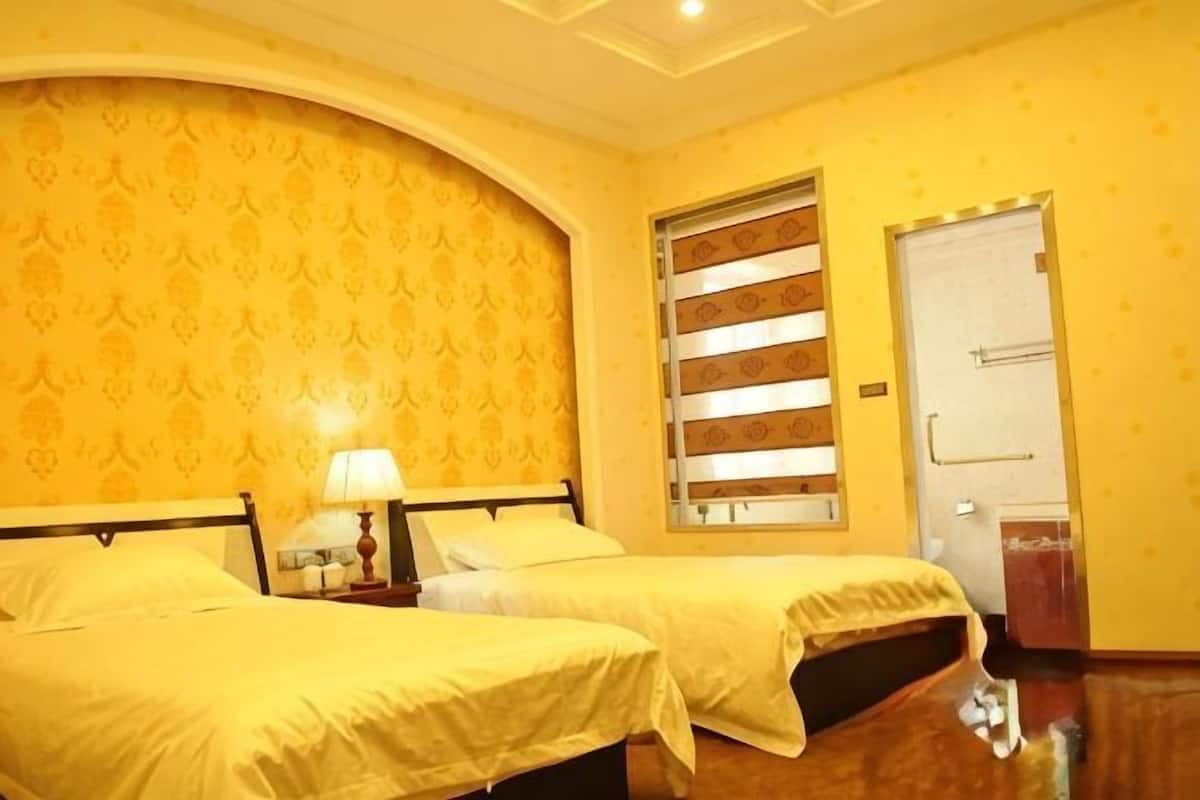 Une chambre d’hôtel avec deux lits, une fenêtre avec des stores, une porte et un papier peint à motifs.