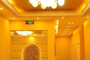 Un pasillo de hotel con un elemento decorativo circular en la pared, una lámpara en el techo y un letrero con caracteres chinos.