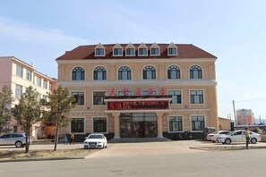Um edifício de vários andares com telhado de telhas vermelhas e uma placa.