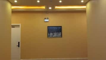A hallway with a carpeted floor, a door on the left, and a framed picture on the wall.