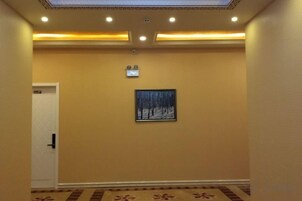A hallway with a carpeted floor, a door on the left, and a framed picture on the wall.