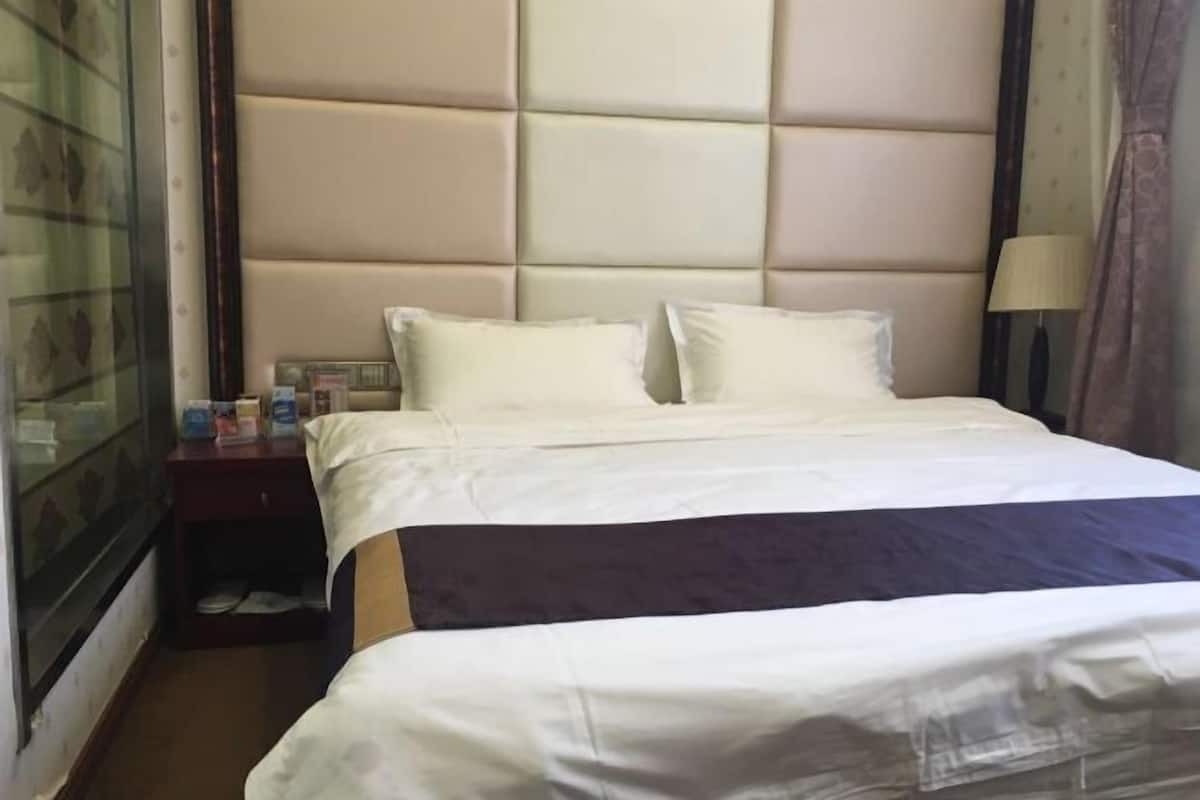 Une chambre d’hôtel avec un grand lit, une table de chevet, une lampe et une porte en verre.