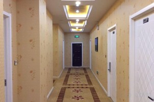 Un pasillo de hotel con piso alfombrado, puertas a ambos lados y un techo con iluminación empotrada.