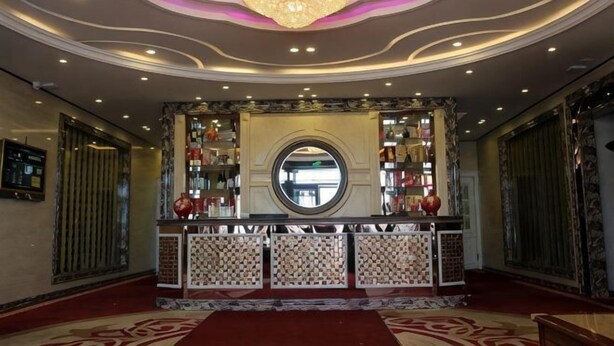 A lobby with a chandelier, a reception desk, and a circular mirror.