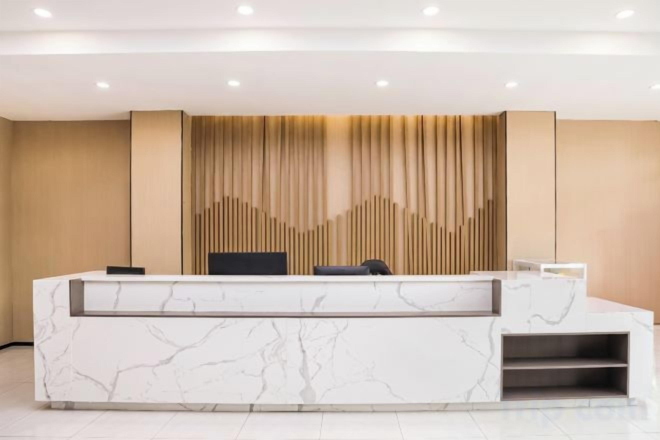 A reception desk with a marble top, a black chair, and a wall-mounted panel with vertical lines.