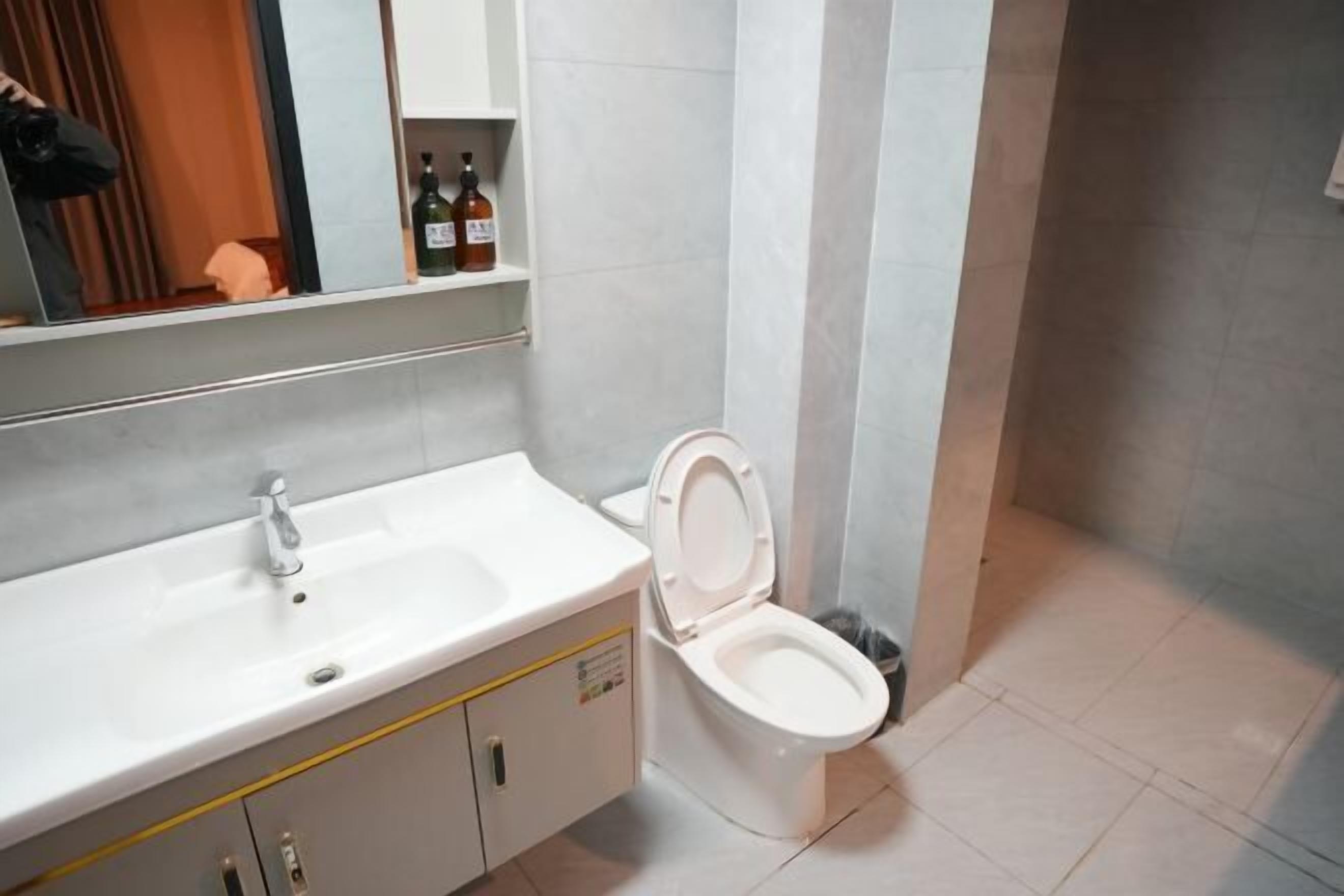 A bathroom with a white sink, mirror, and toilet.