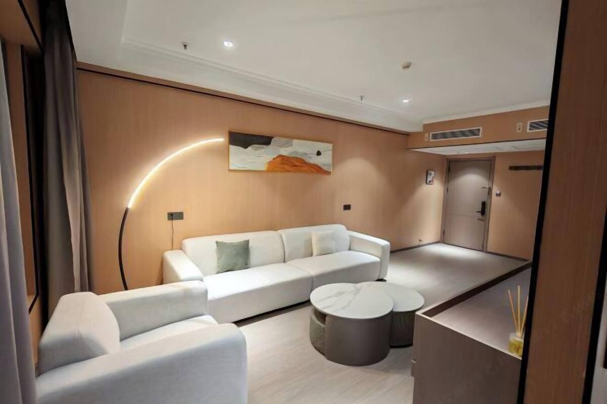 A modern living room with a white sofa, a coffee table, and a wall-mounted artwork.
