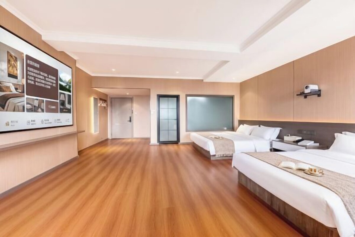 A hotel room with a wooden floor, two beds, a TV, and a wall-mounted shelf.