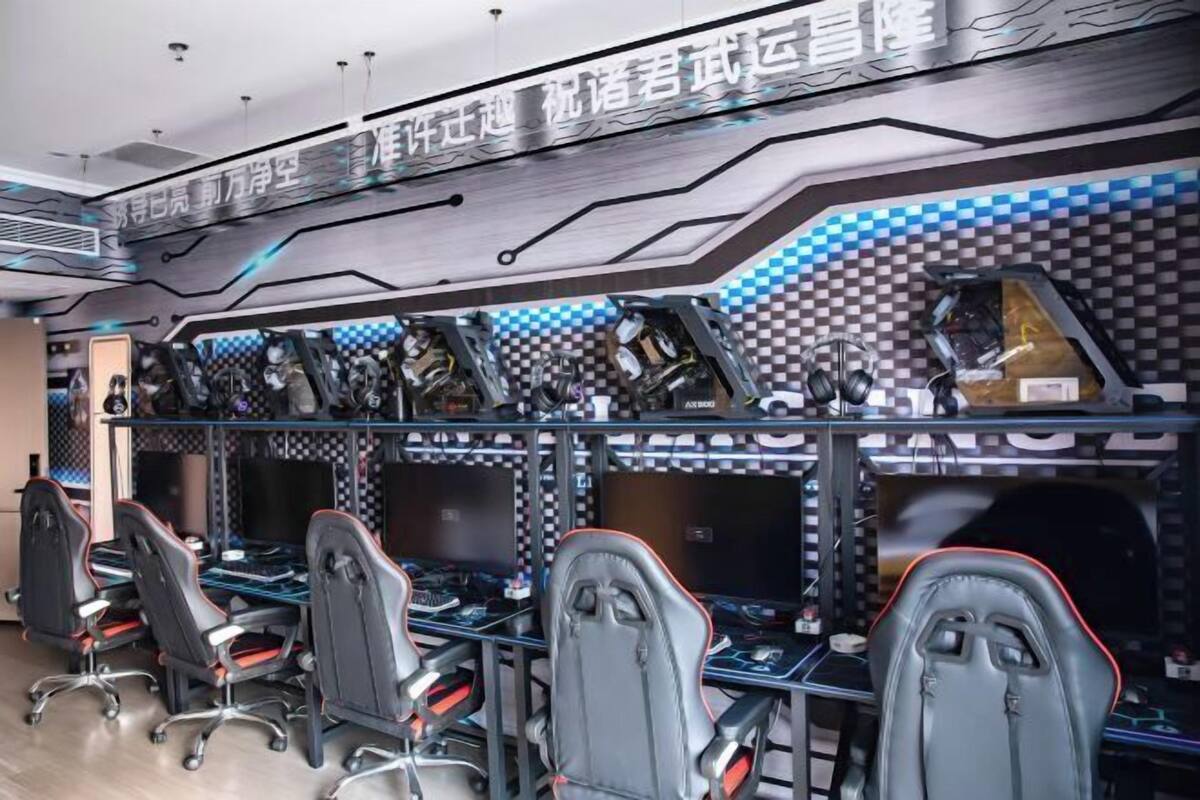 A gaming lounge with multiple gaming stations, each equipped with a chair, desk, and computer.