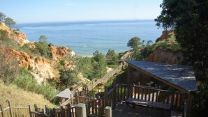 Um deck de madeira com vista para o oceano e falésias rochosas.