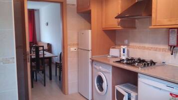 Cocina compacta con lavadora, microondas y cocina a gas.