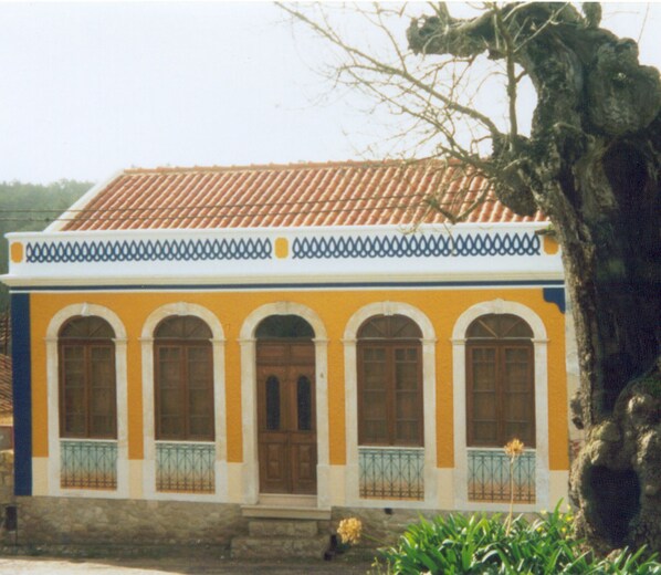 A building with a yellow facade, white trim, and a tiled roof.