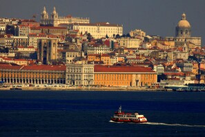 A cityscape with historic buildings, a prominent cathedral, and a river with a ferry.