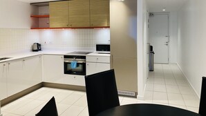 Une cuisine moderne avec des armoires blanches, un four encastré, un four à micro-ondes et une machine à café.
