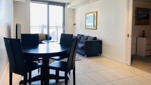 Un salon moderne comprenant un coin repas, de grandes fenêtres, un canapé et un tableau accroché au mur.