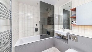 Une salle de bain moderne avec une douche à parois de verre, une baignoire et un meuble-lavabo avec un miroir.