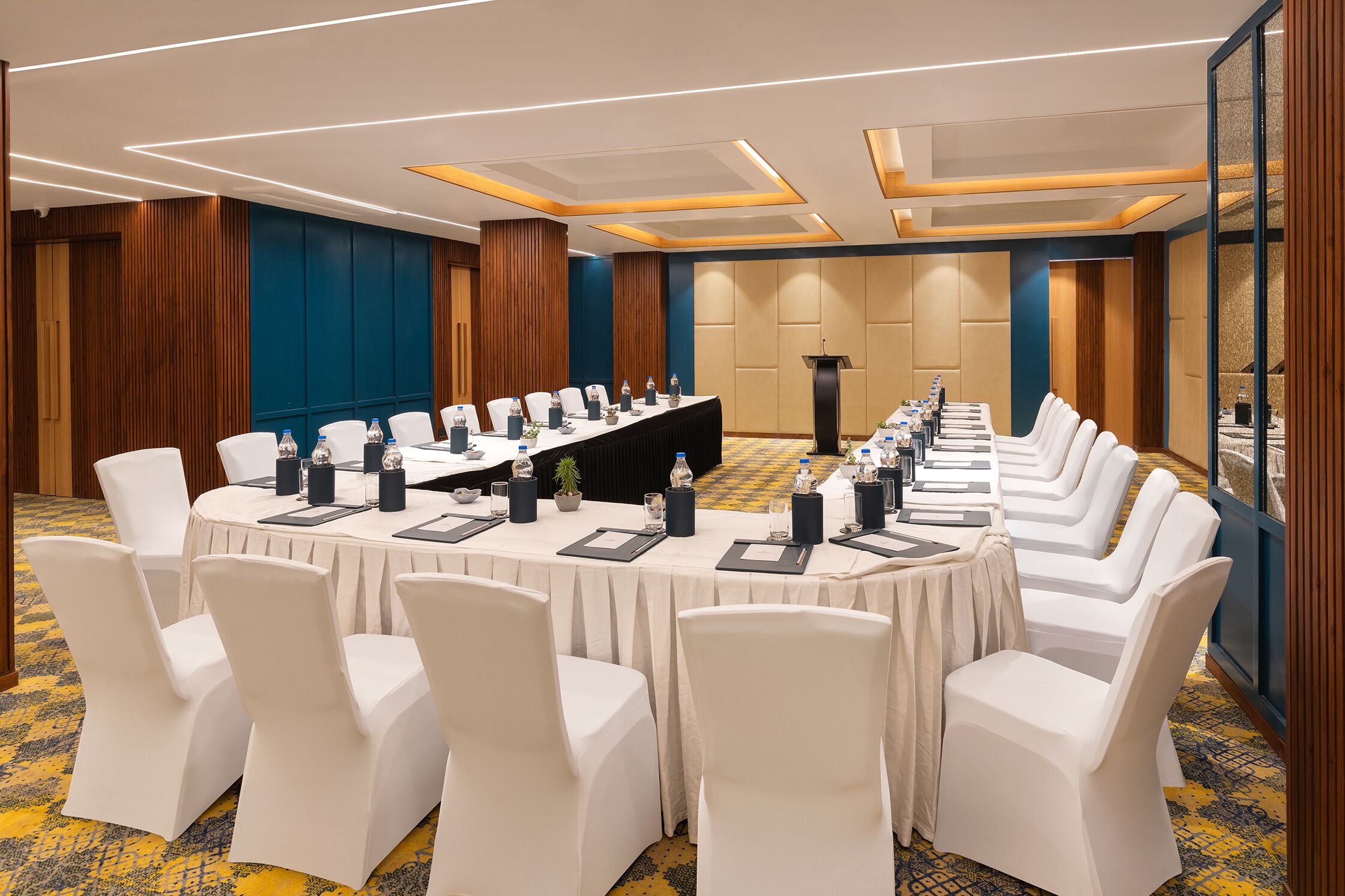 A conference room with a long table, white chairs, and a podium.