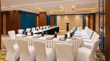 A conference room with a long table, white chairs, and a podium.